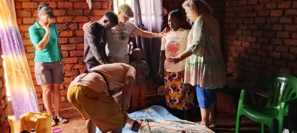 Besucher der Stiftung beten mit einer Familie bei einem Hausbesuch